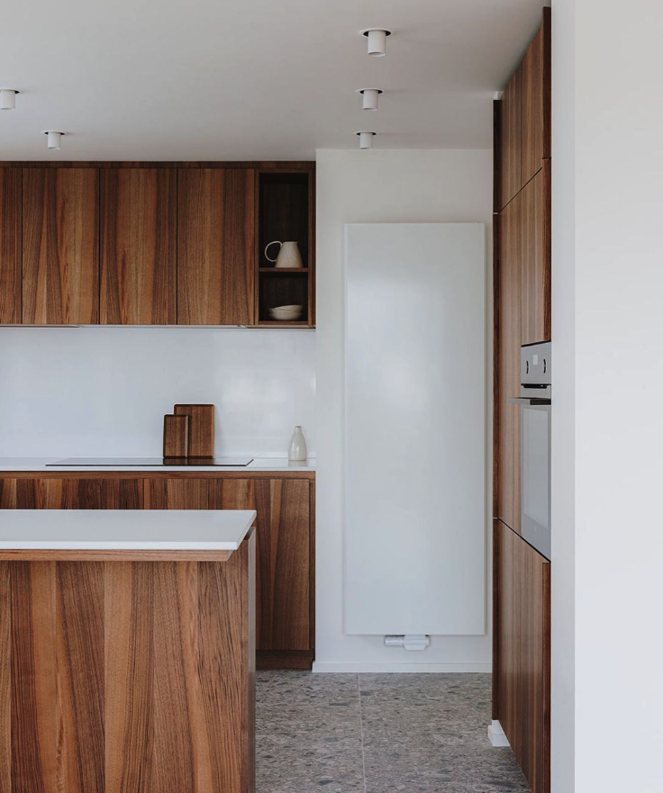 Cuisine moderne avec des armoires en bois, un îlot central blanc et un radiateur mural blanc