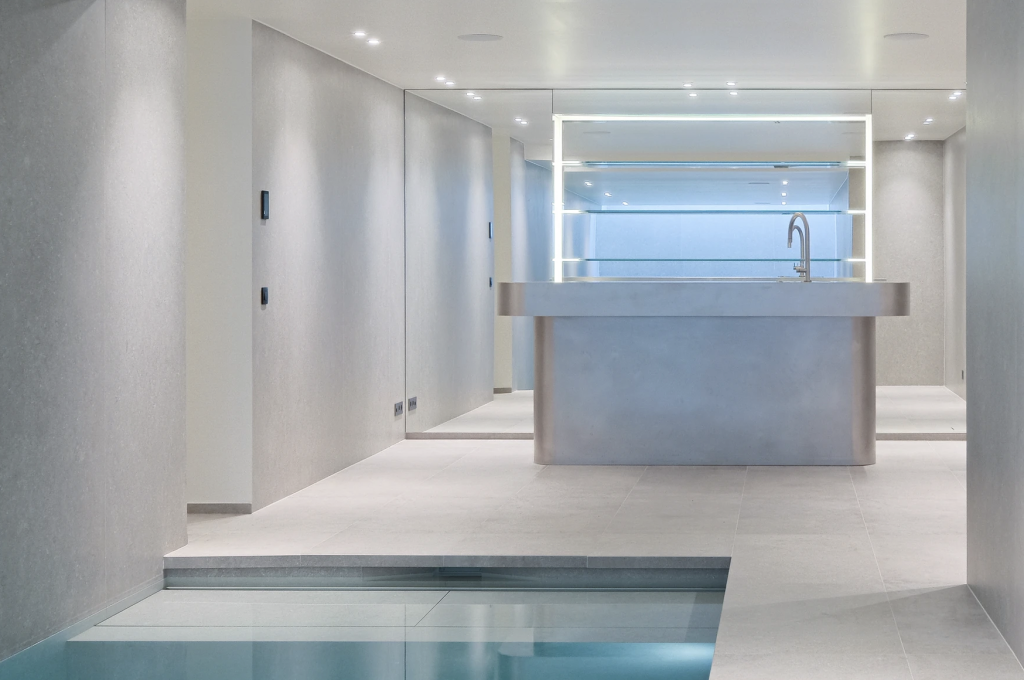 Bar moderne aux lignes épurées avec un évier, entouré de murs gris et d'une piscine intérieure.