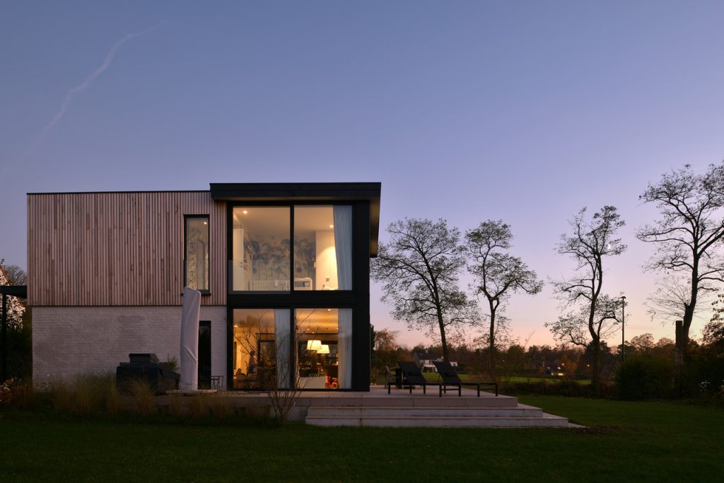 Maison moderne avec façade en bois clair et grandes baies vitrées, au crépuscule