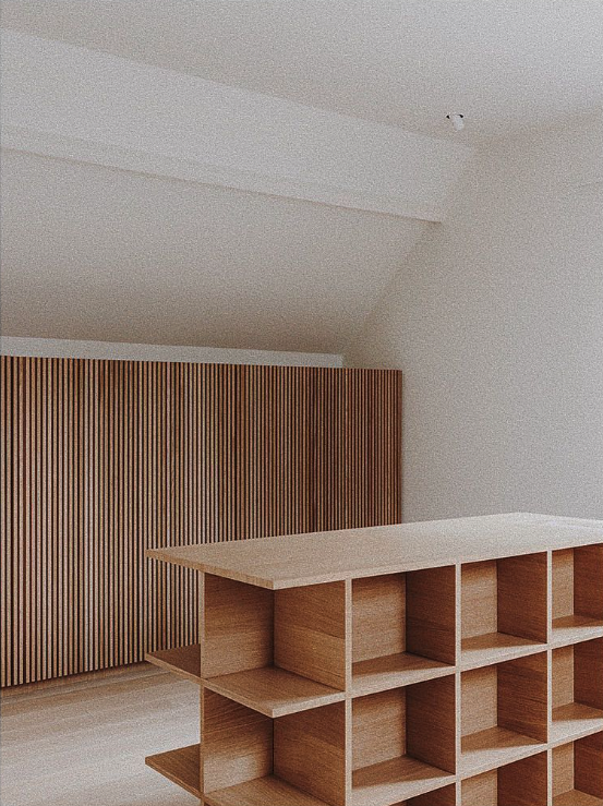Étagère modulable en bois clair devant un mur lambrissé