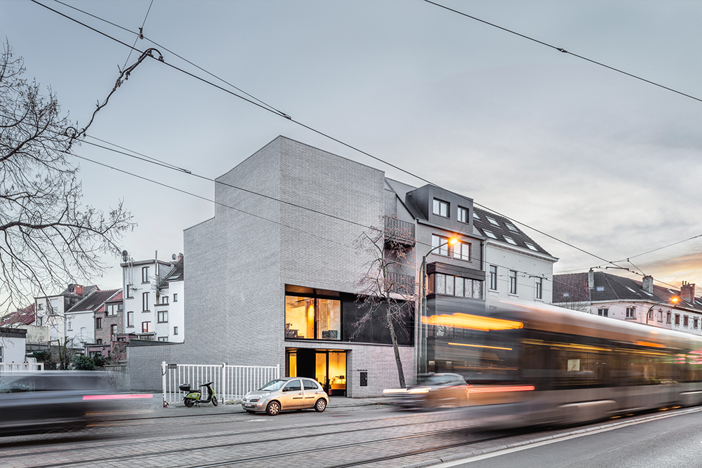 Immeuble moderne en brique claire au bord d’une rue avec tramway flou en mouvement